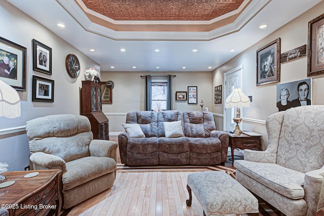 living area featuring light wood-type flooring, a raised ceiling, and crown molding