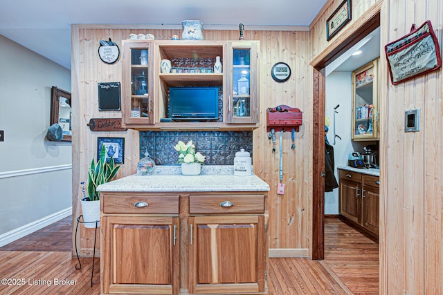 kitchen featuring light wood-style flooring, glass insert cabinets, and backsplash