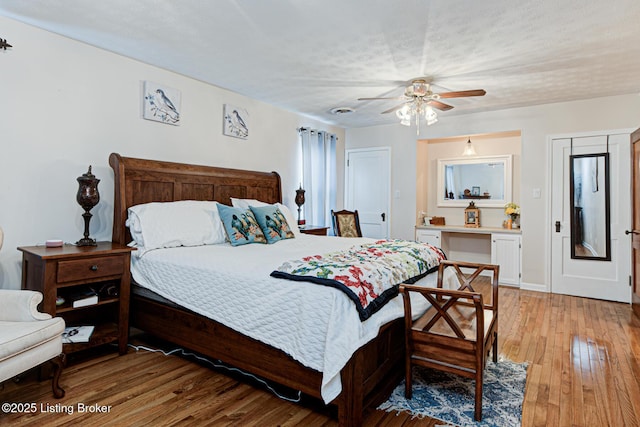 bedroom with ceiling fan, a textured ceiling, light wood-type flooring, and baseboards