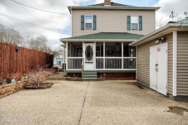 view of front of property with a sunroom, a chimney, fence, and a patio