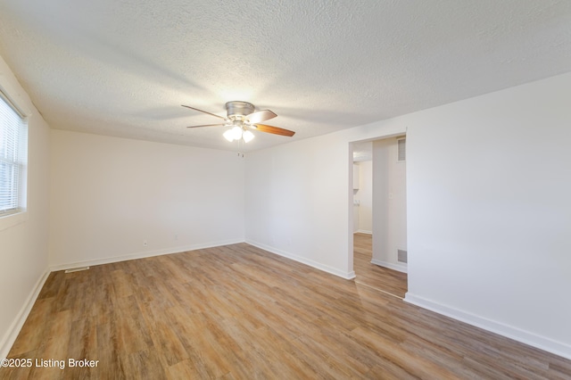 spare room featuring baseboards, visible vents, a ceiling fan, and light wood-style floors