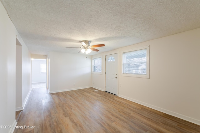 foyer entrance featuring ceiling fan, baseboards, a healthy amount of sunlight, and wood finished floors