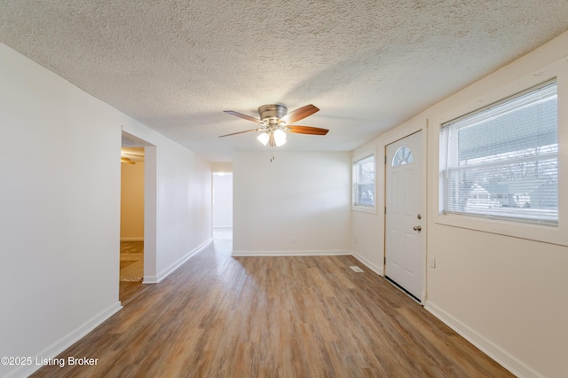 interior space with a ceiling fan, baseboards, and wood finished floors