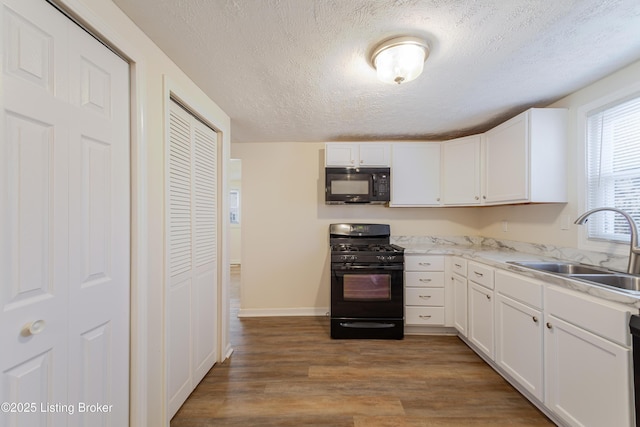 kitchen featuring a sink, light wood-style floors, black appliances, and white cabinets