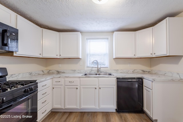 kitchen featuring white cabinetry, black appliances, light wood-type flooring, and a sink