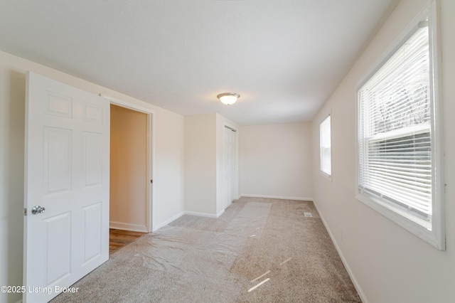 empty room with visible vents, baseboards, and light carpet