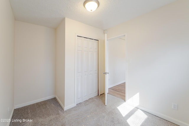 unfurnished bedroom with a closet, baseboards, a textured ceiling, and carpet flooring