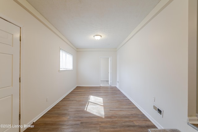 empty room with visible vents, baseboards, a textured ceiling, and wood finished floors