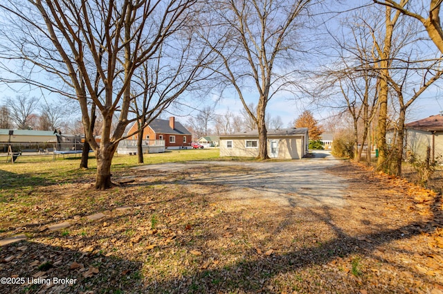 view of yard featuring a trampoline and driveway