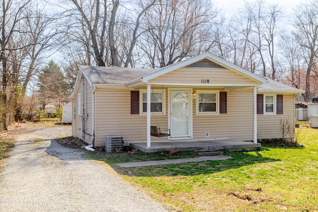 bungalow featuring a porch, a front lawn, gravel driveway, and central AC