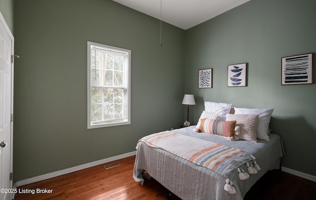 bedroom with hardwood / wood-style floors, baseboards, and visible vents