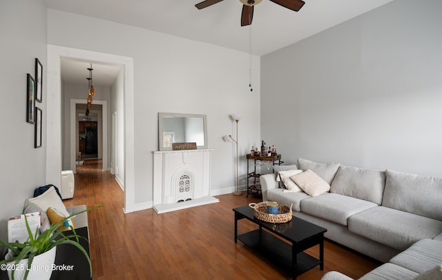 living area with baseboards, ceiling fan, and wood finished floors