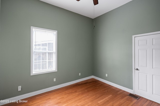 empty room with ceiling fan, visible vents, baseboards, and hardwood / wood-style floors