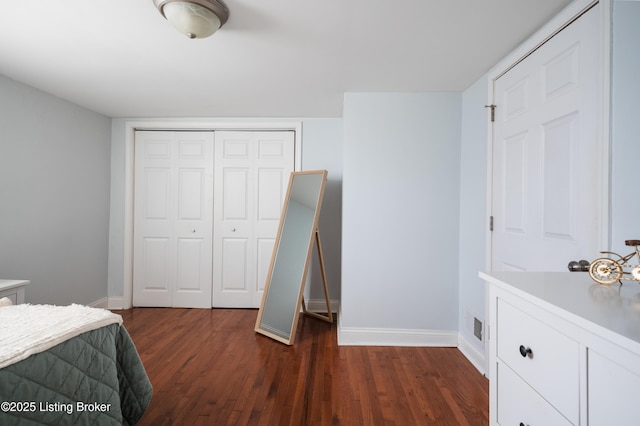 bedroom with dark wood finished floors, baseboards, and a closet