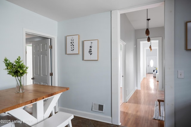 hall featuring dark wood finished floors, visible vents, and baseboards