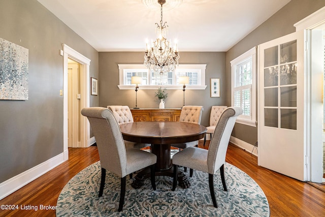 dining area with a chandelier, wood finished floors, and baseboards