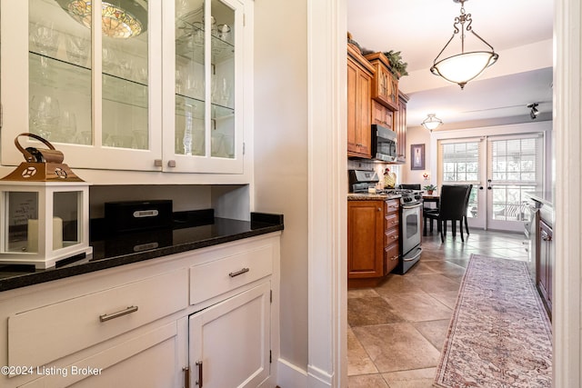 kitchen with glass insert cabinets, appliances with stainless steel finishes, brown cabinets, and pendant lighting