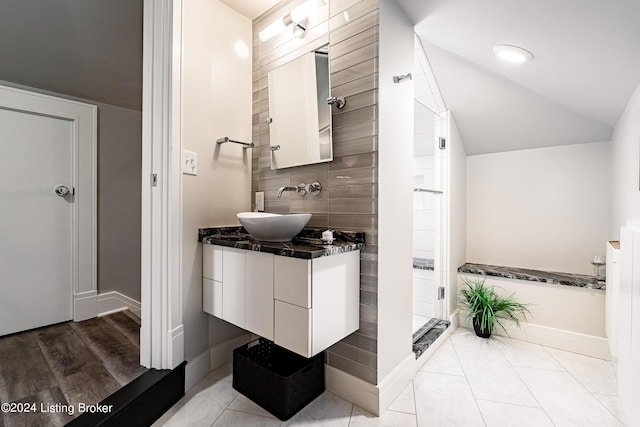 bathroom featuring a stall shower, tile patterned floors, vaulted ceiling, and vanity