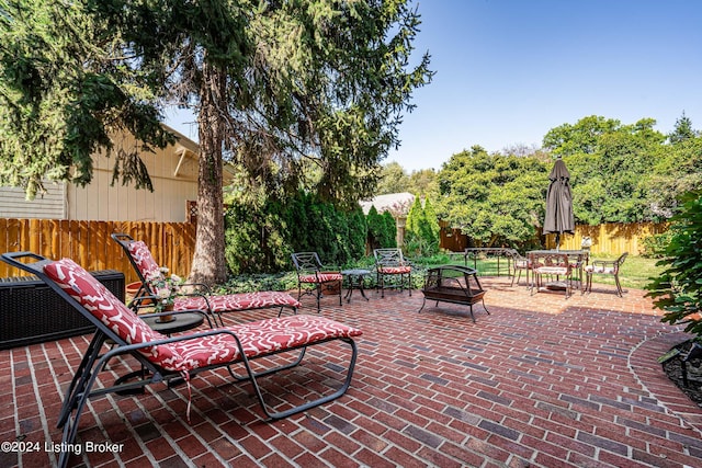 view of patio with a fire pit, outdoor dining space, and fence