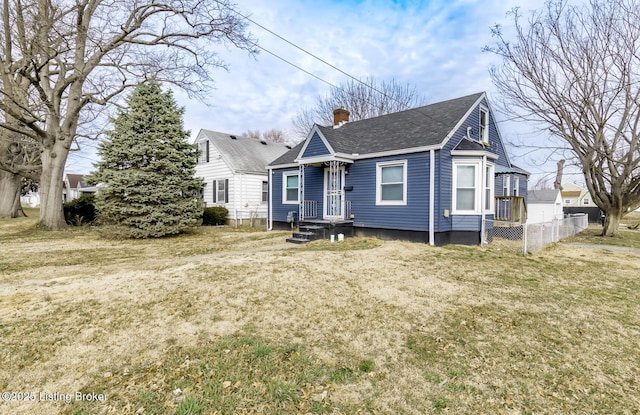 bungalow featuring a shingled roof, a front yard, fence, and a chimney