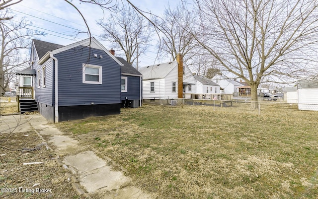 back of property with central AC unit, fence, roof with shingles, a lawn, and a chimney