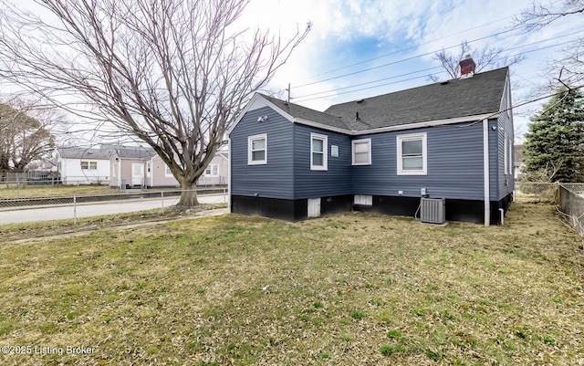 rear view of house with a yard, fence, cooling unit, and roof with shingles