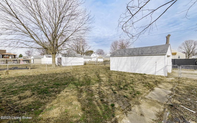 view of yard with an outdoor structure, fence, and a gate