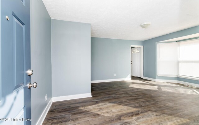 spare room featuring a textured ceiling, wood finished floors, and baseboards