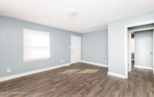 unfurnished room with a textured ceiling, baseboards, and dark wood-style flooring