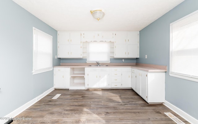 kitchen featuring dark wood-type flooring, a sink, white cabinetry, baseboards, and open shelves