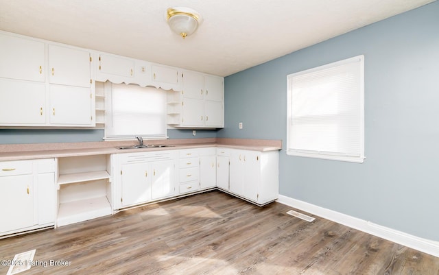 kitchen with open shelves, a sink, white cabinetry, and baseboards