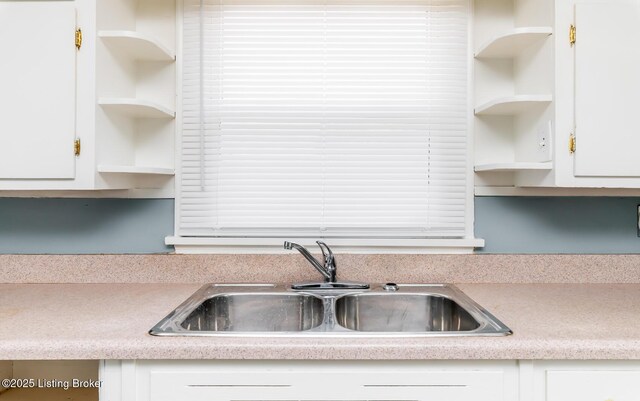 kitchen featuring white cabinetry, light countertops, a sink, and open shelves