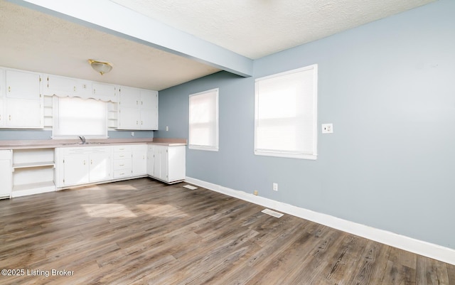 kitchen with open shelves, visible vents, white cabinets, a textured ceiling, and baseboards