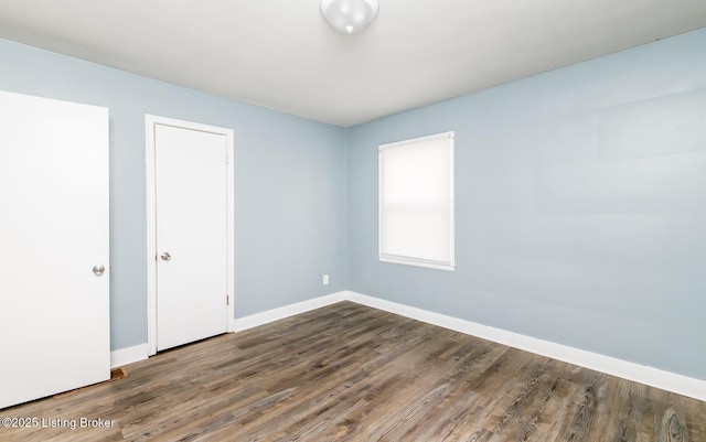 spare room featuring baseboards and wood finished floors