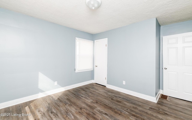 spare room featuring dark wood-style floors, baseboards, and a textured ceiling