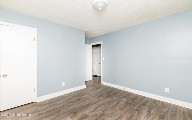 unfurnished bedroom featuring a textured ceiling, baseboards, and wood finished floors