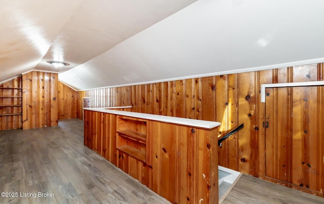 bonus room with lofted ceiling, wooden walls, and wood finished floors