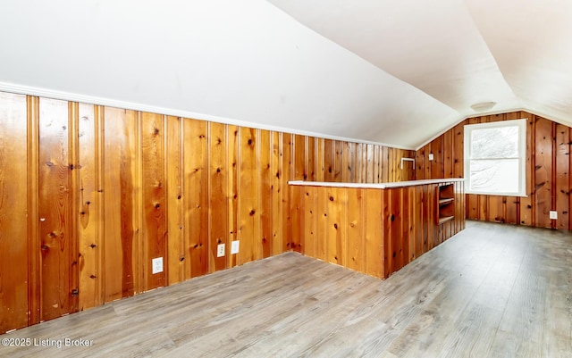 bonus room featuring vaulted ceiling, wood finished floors, and wooden walls