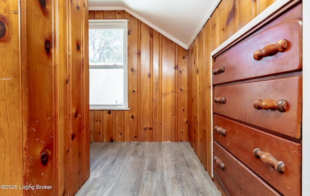 interior space with ornamental molding, lofted ceiling, and wooden walls