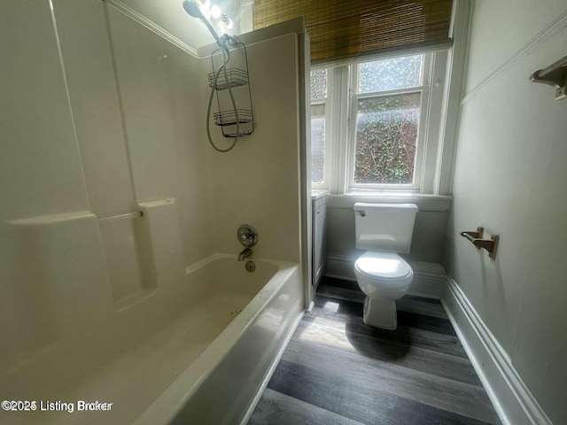 full bath with bathing tub / shower combination, wood finished floors, toilet, and baseboards