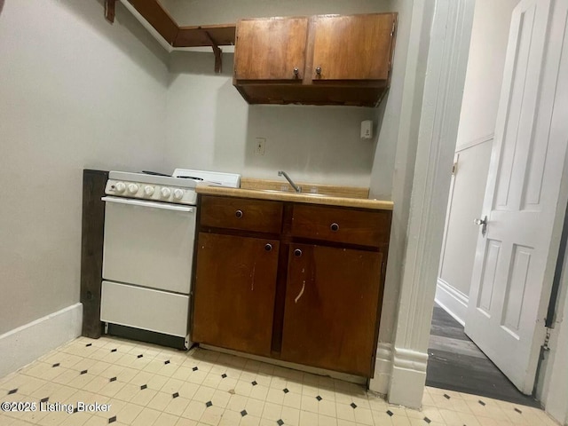 kitchen featuring a sink, light floors, light countertops, and white range with electric cooktop