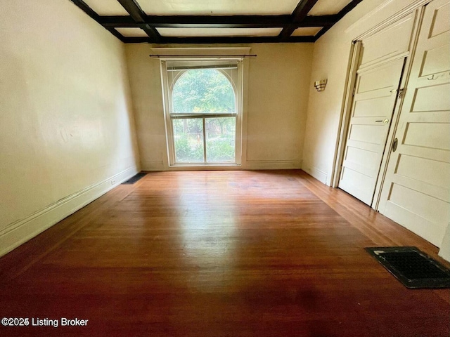 unfurnished room with baseboards, visible vents, coffered ceiling, and wood finished floors