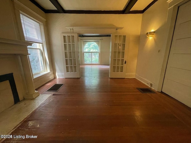 interior space with a healthy amount of sunlight, beamed ceiling, and wood finished floors