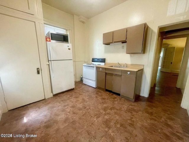 kitchen featuring light countertops, white appliances, and a sink