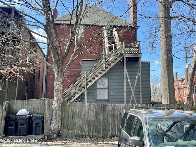 exterior space featuring brick siding, a chimney, and fence