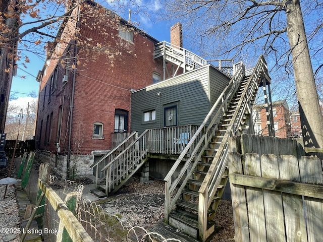 back of house with brick siding, stairway, and fence