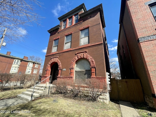 view of front facade featuring brick siding and fence