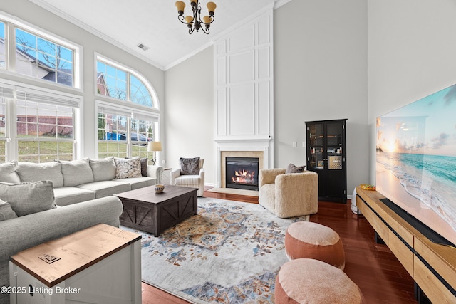 living room featuring a chandelier, high vaulted ceiling, a fireplace, wood finished floors, and ornamental molding