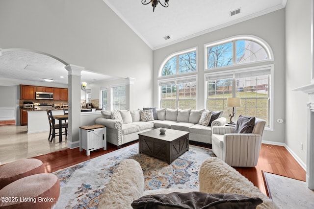 living room with light wood finished floors, visible vents, and crown molding