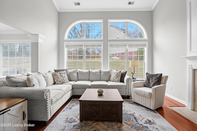 living room featuring crown molding, visible vents, and wood finished floors